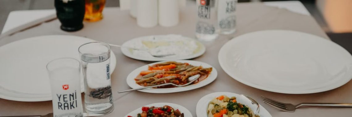 From above of served table with assorted delicious appetizers with beverages and dishware on veranda of restaurant in evening
